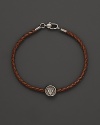 Silver Gucci charm on a braided brown natural leather bracelet.