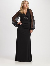 This stunning gown was designed to accentuate your shape, thanks to a striking embellishment at a subtly gathered bust and sheer sleeves offering glamorous arm coverage.V-necklineSheer, bell sleevesEmbellishment at gathered bustConcealed back zipperFully linedAbout 45 from natural waist95% polyester/5% spandexDry cleanMade in USA of imported fabric